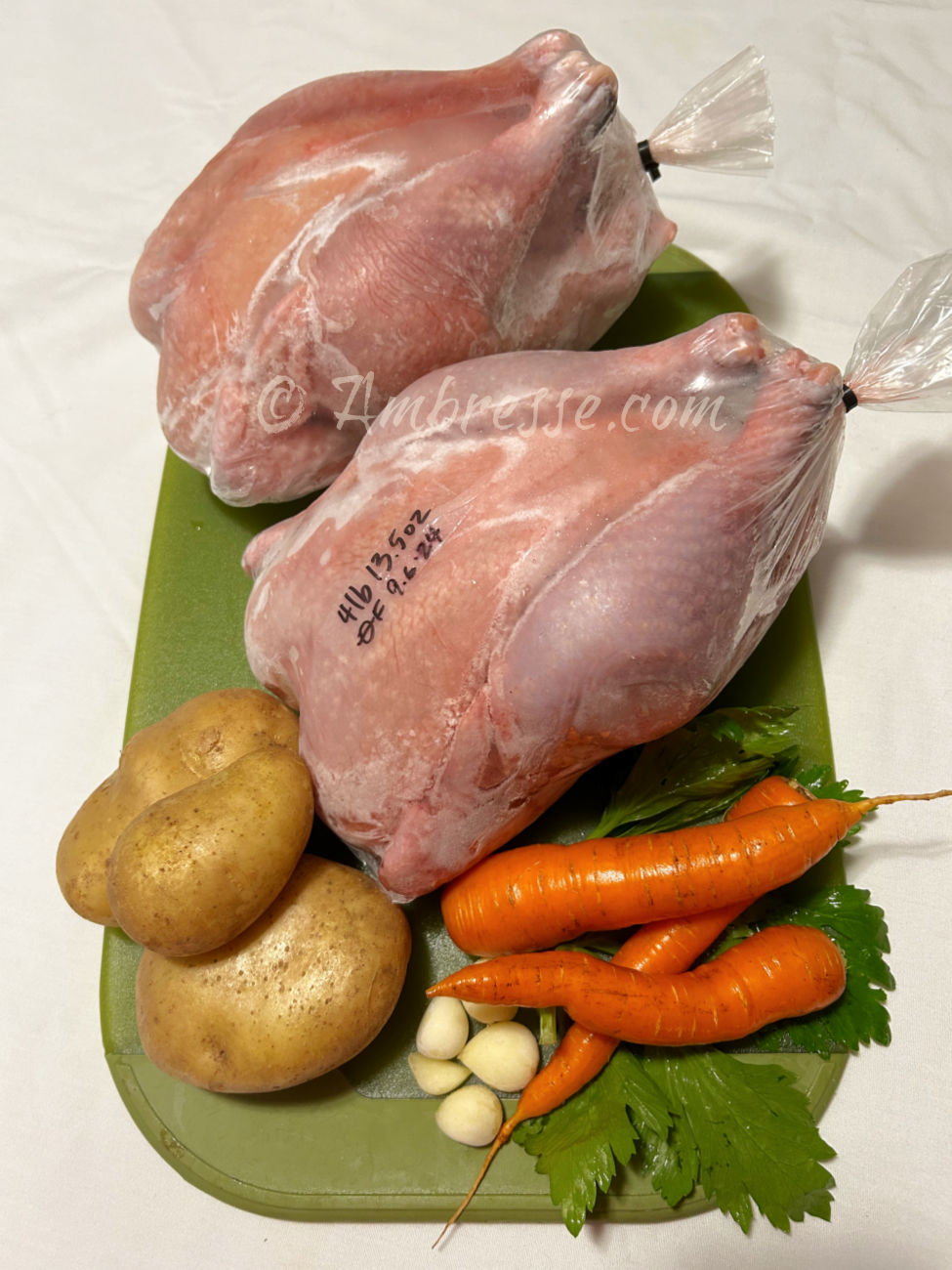 Two processed American Bresse birds, with potatoes, garlic, carrots, and celery all raised by Ambresse Acres.